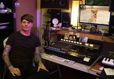 a man with tattoos sitting in front of a recording equipment set up on a desk