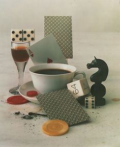 a cup of coffee sitting on top of a table next to dice and other items