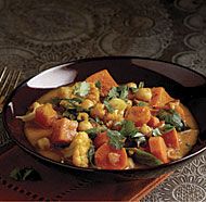 a brown bowl filled with food and garnished with cilantro, cauliflower, and green leaves