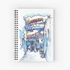 a watercolor drawing of an alleyway with shops and flowers on the awnings spiral notebook