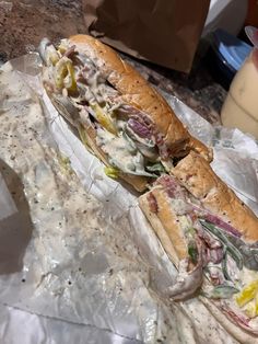 two sub sandwiches sitting on top of plastic wrap