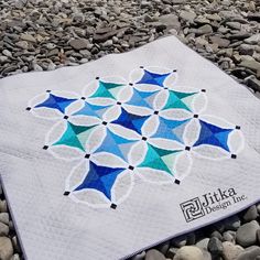 a blue and white quilt sitting on top of rocks