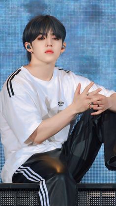 a man sitting on top of a bench wearing black pants and a white t - shirt