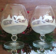 two wine glasses sitting on top of a table next to pine cones and christmas decorations