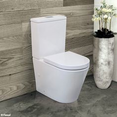 a white toilet sitting next to a vase with flowers