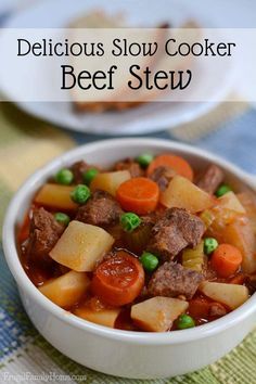 a white bowl filled with beef stew and carrots on top of a blue table cloth