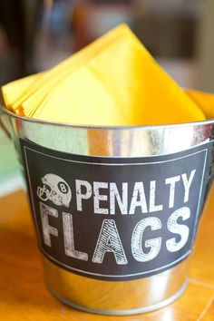 a metal bucket filled with yellow napkins on top of a wooden table