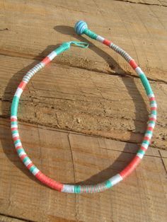 a colorful necklace is sitting on a wooden table with a blue and white bead around it