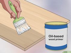 a person using a brush to paint a wooden table with an oil - based primer