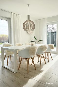 a dining room table with white chairs and a large window