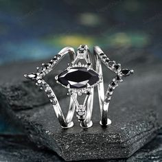 a black and white diamond ring sitting on top of a rock