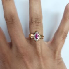 a woman's hand with a ring on it that has a pink stone in the middle