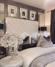 a white bed sitting in a bedroom next to two lamps and pictures on the wall