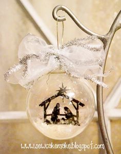 a glass ornament with a nativity scene on it hanging from a metal pole