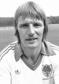 a young man sitting in front of a soccer field wearing a uniform with an eagle on it