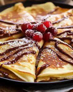 crepes with chocolate sauce and cherries are on a pancake platter