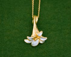 The lily is an iconic flower synonymous with summer.The gentle curves and subtle finish of this flower design gives this series an elegant and timeless look. With a base of high purity silver and plated with 23K Gold, the gold has been partially scraped away to reveal the silver underneath. The Silver-only version has also been partially scraped to create the contrast in textures.Pendant length: approximately 21mmChain length: 40cm (15.8 in), 45cm (17.7 in) or 50cm (19.7 in)Pendant material: Sil Gold Plated Flower Pendant Necklace, Water Lily Jewelry, Lily Flower Necklace, Nature-inspired White Flower Pendant Jewelry, Elegant Yellow Flower Pendant Necklace, Lily Jewelry, Ethereal Jewelry, Lily Necklace, Japanese Jewelry