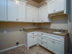 an empty kitchen with white cabinets and granite counter tops, is shown in this image