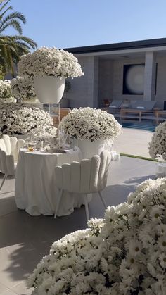 an outdoor dining area with tables and chairs covered in white flowers