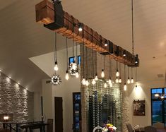 a dining room table and chairs with wine bottles hanging from the ceiling above it in front of windows