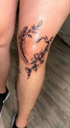 a woman's legs with flowers and leaves on them in the shape of a heart