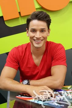 a young man sitting at a table smiling for the camera