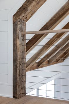 an old wooden beam in the corner of a room with white walls and wood flooring