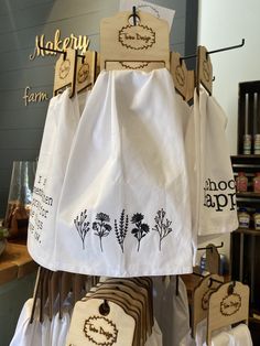 some white towels hanging on a rack with wooden tags attached to them and other items in the background