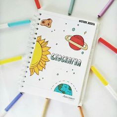 an open spiral notebook sitting on top of colored pencils