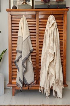 two towels are hanging on a wooden cabinet