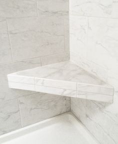 the corner of a shower with marble tile