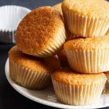 a white plate topped with muffins on top of a black table next to cupcake tins