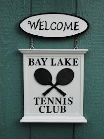 a sign that says welcome to the bay lake tennis club hanging on a green wall