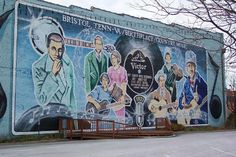 a large mural on the side of a building with people playing guitar and singing in front of it