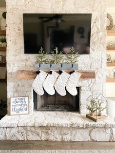 a fireplace with stockings hanging from the mantel and christmas decorations on top of it