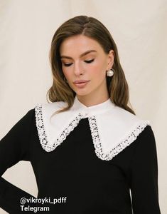 a woman wearing a black and white dress with an embroidered collar