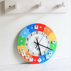 a multicolored clock on the wall with numbers and letters in front of it