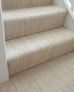 carpeted stairs with white handrails and beige carpet