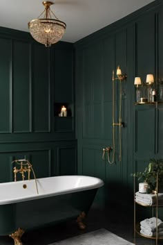 a bathroom with green walls, gold fixtures and a claw foot tub in the middle