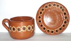 two brown cups and a plate sitting on a table next to each other with dots painted on them