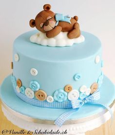 a blue and white cake with a teddy bear on top