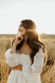 a woman in a white dress is standing in the middle of a field with tall grass