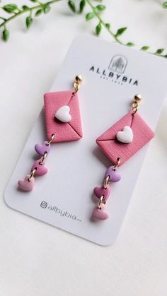 pink and white earrings with hearts hanging from the end of each earring, sitting on top of a card