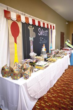 a long table with lots of desserts on top of it in front of a chalkboard sign