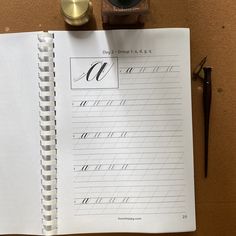 an open notebook with cursive writing on it next to a pen and inkwell