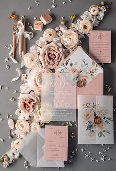 the wedding stationery is laid out on top of each other, including pink and white flowers