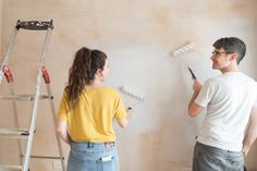 a man and woman are painting the walls together