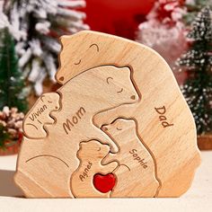 a wooden bear with a heart in its paws on a table next to christmas trees