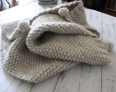 a knitted blanket sitting on top of a wooden table