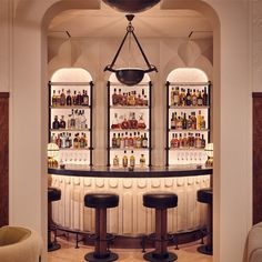 a bar with three stools in front of it and several bottles on the shelves